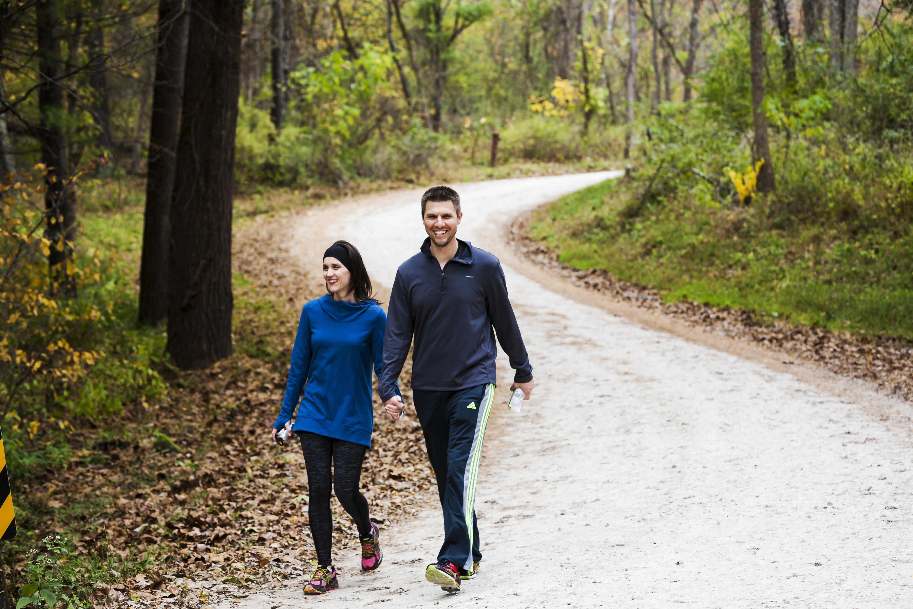 a man and woman walking on a dirt road