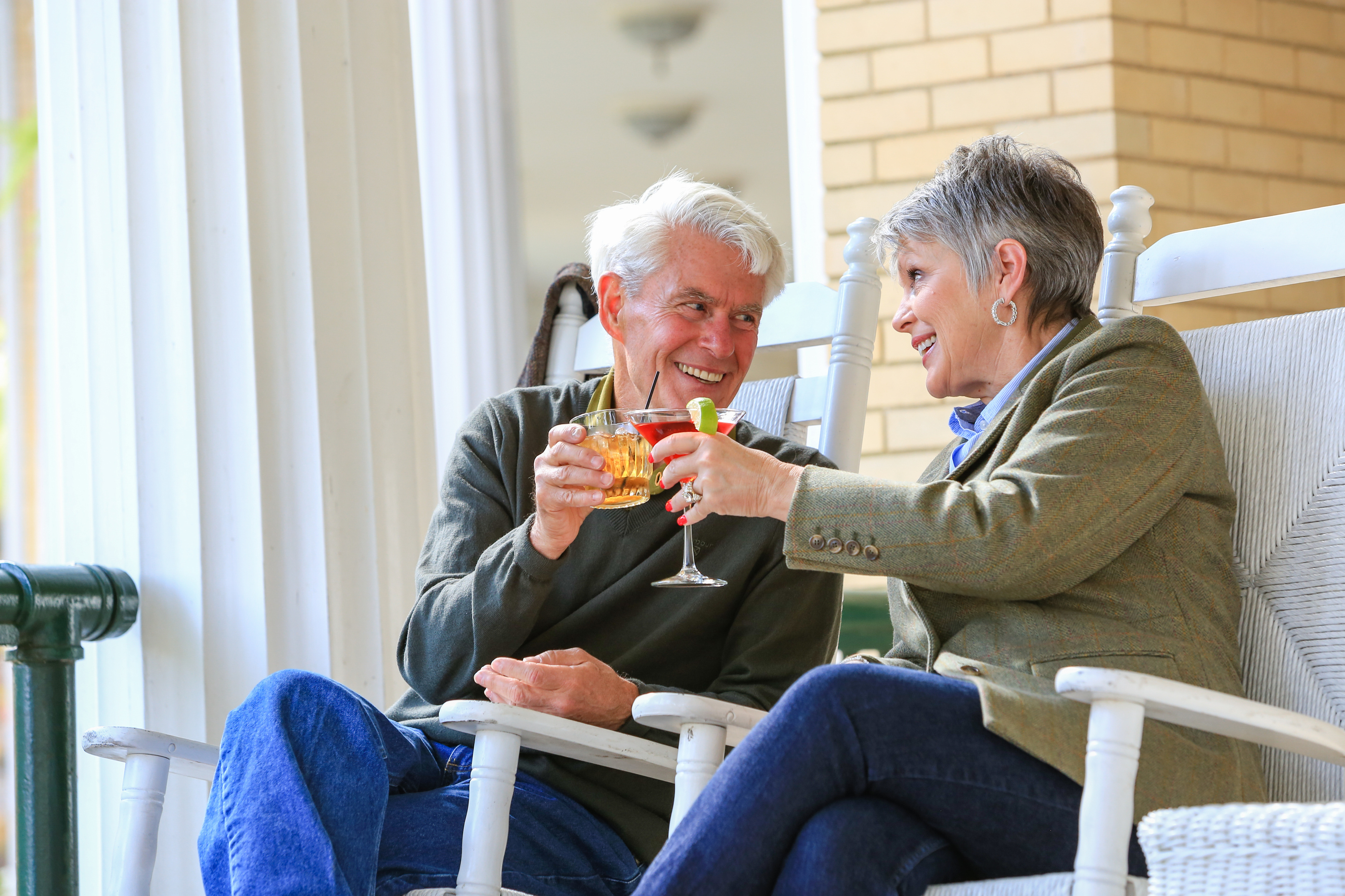 a man and woman sitting in rocking chairs and holding drinks