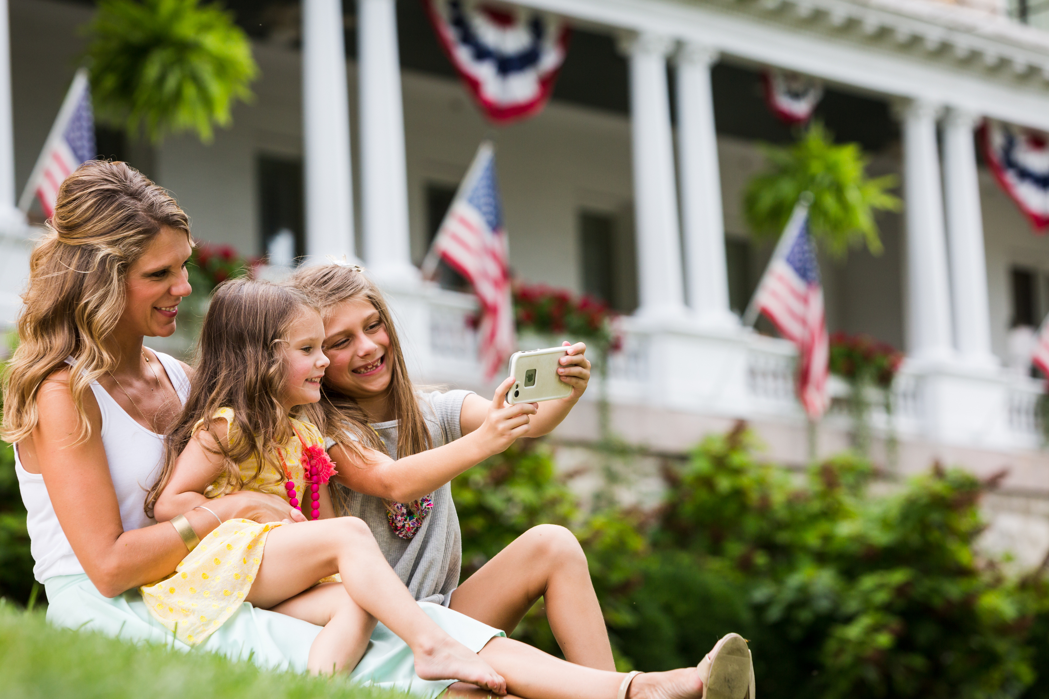 a group of people sitting on grass taking a selfie