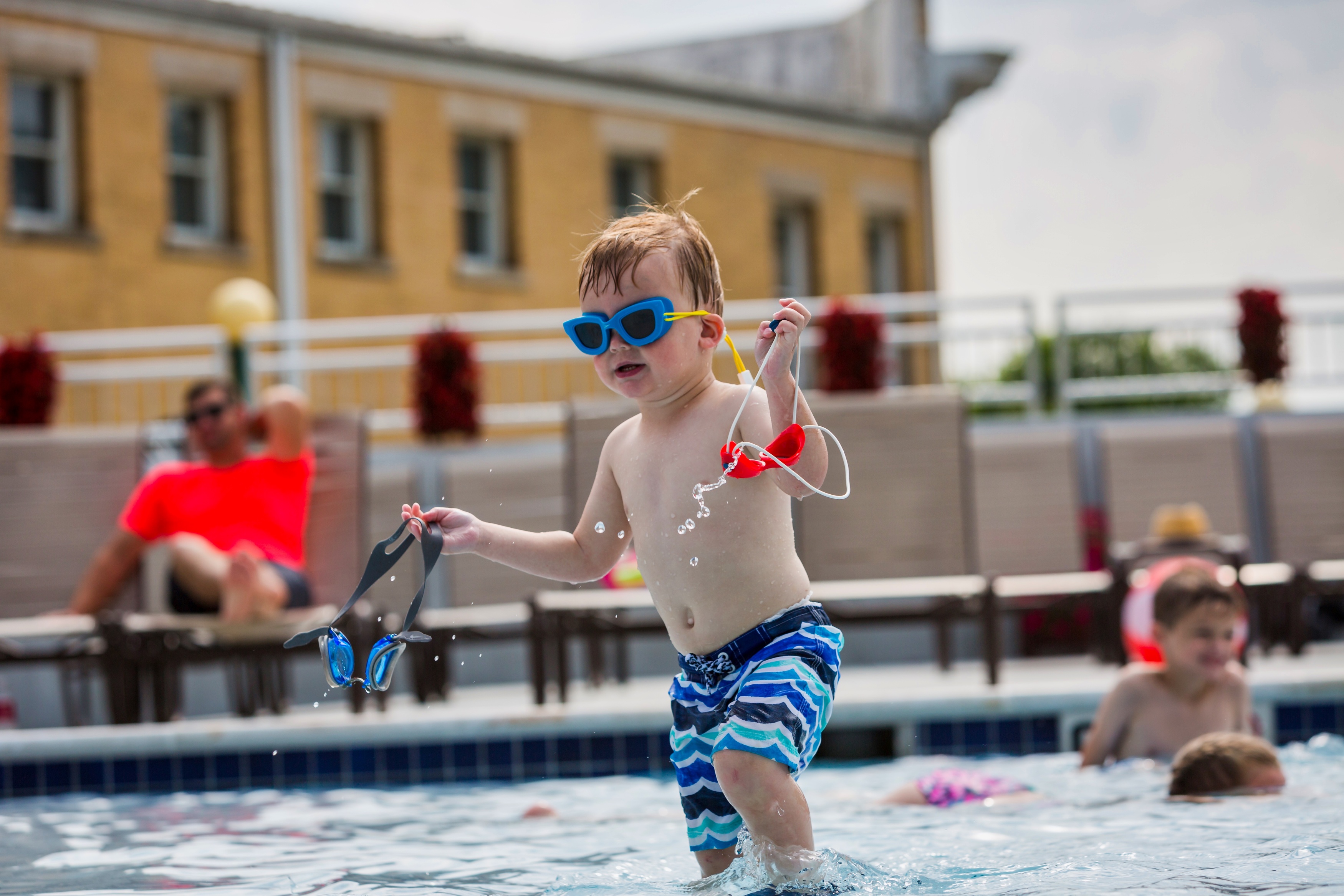 a child in a pool holding goggles and a goggles