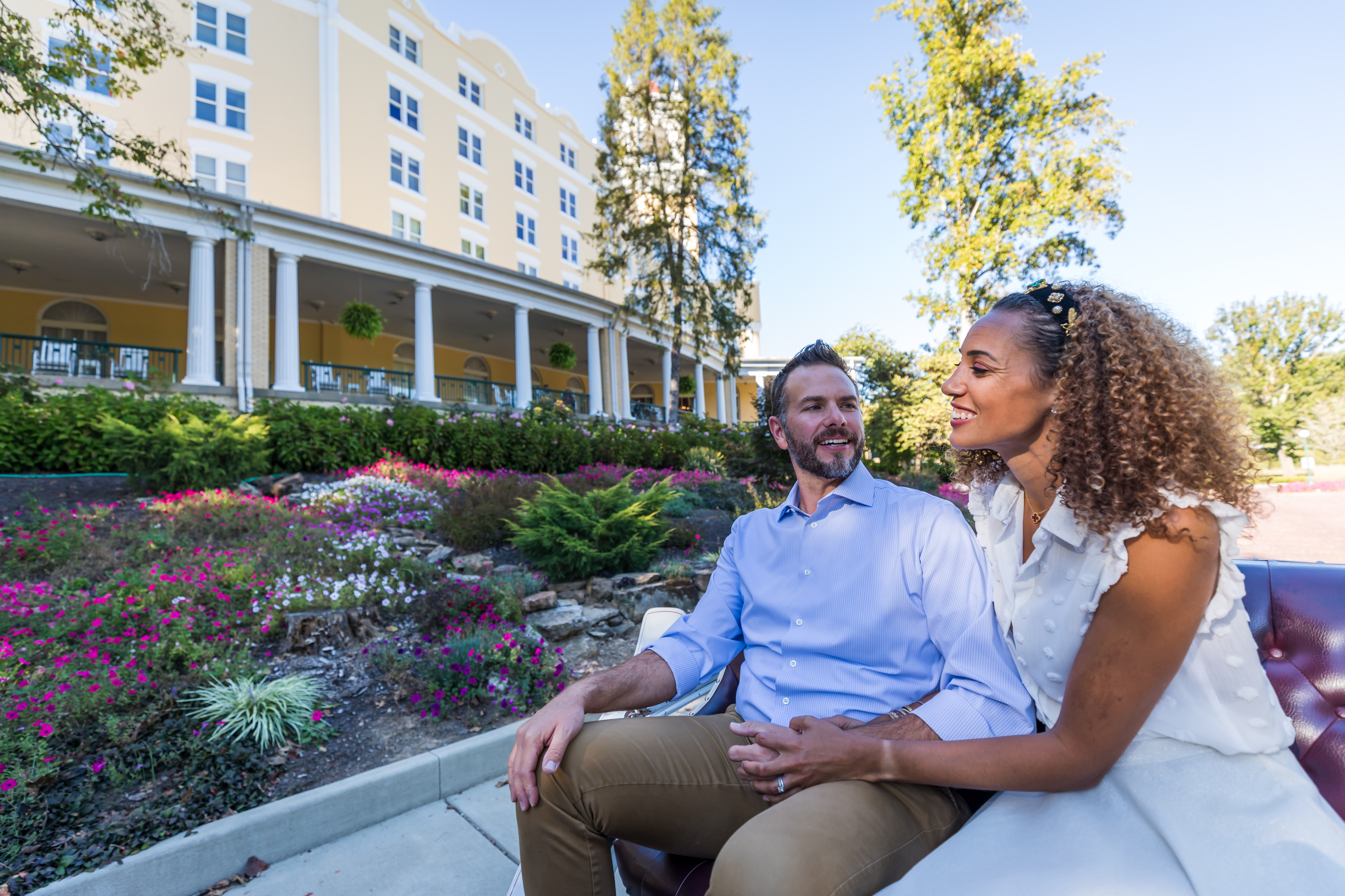 a man and woman sitting on a bench in front of a building