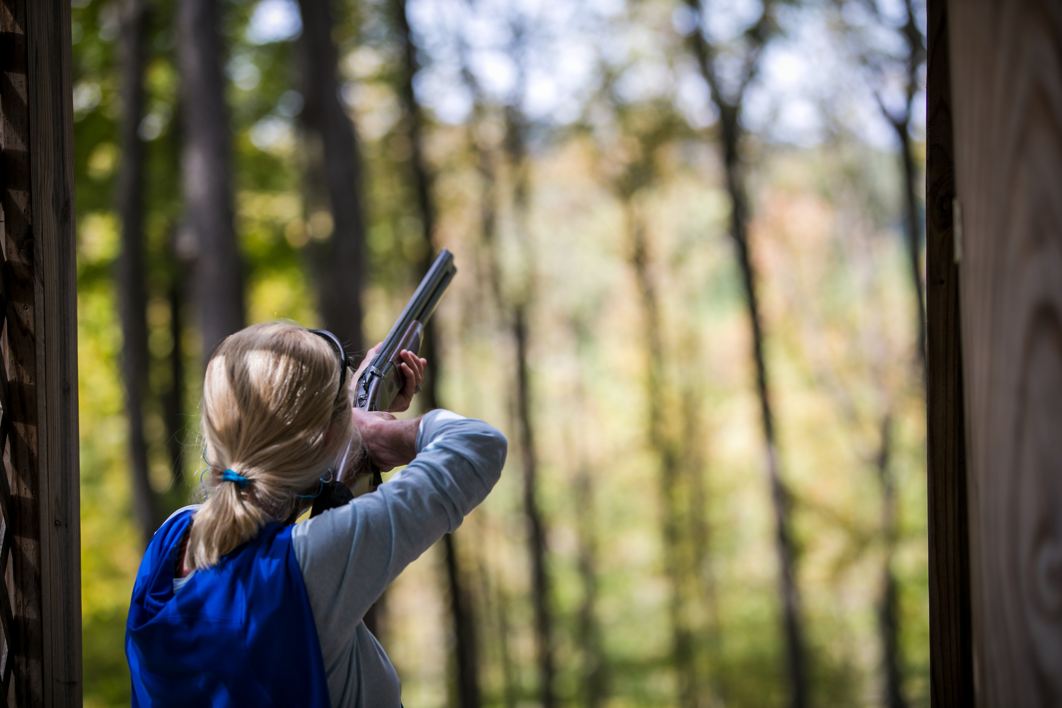 a woman aiming a gun in the woods