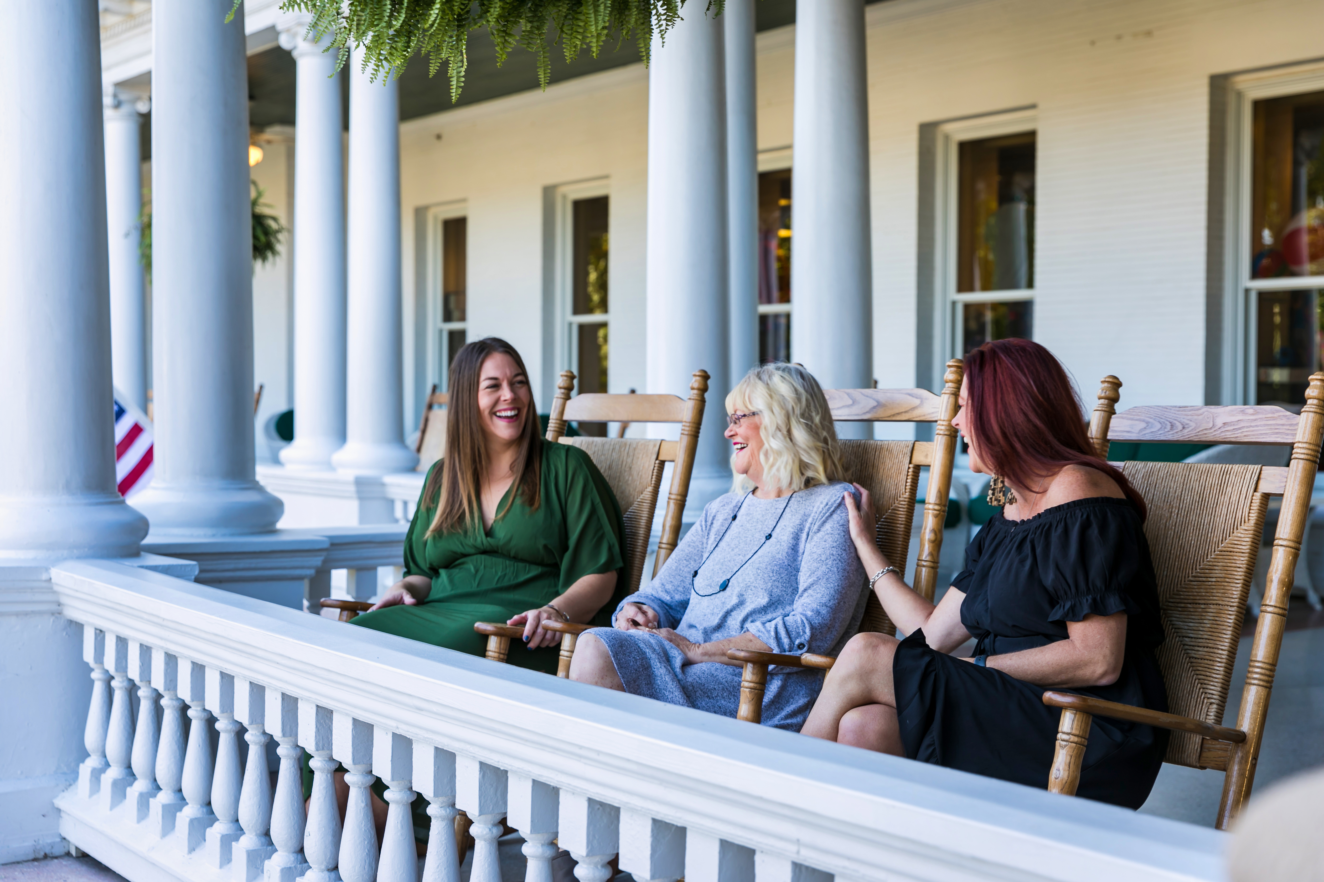 a group of women sitting on chairs on a porch