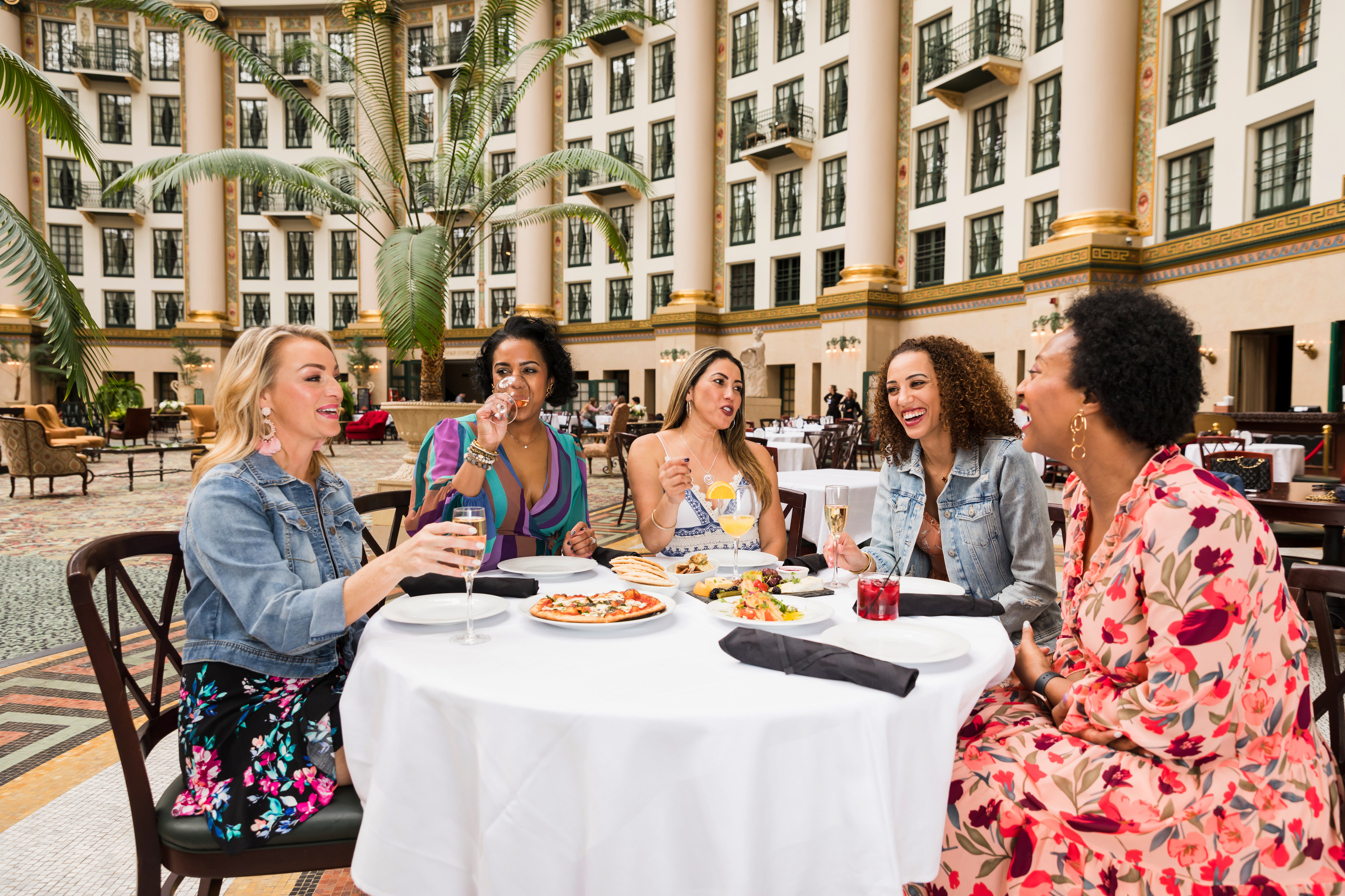 a group of women sitting at a table with food and drinks