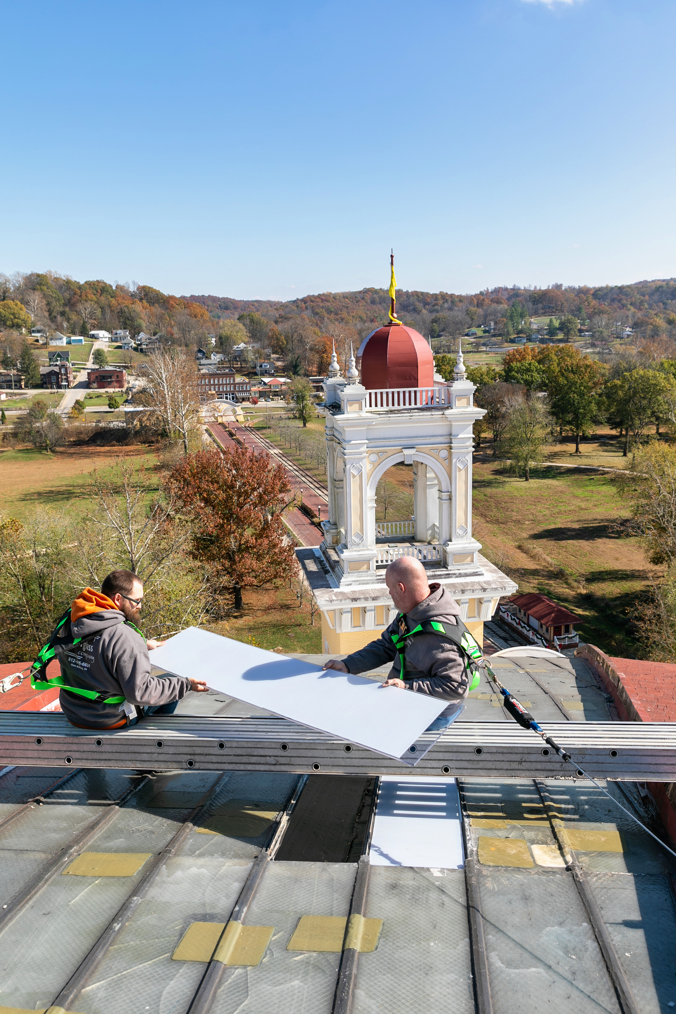 a two men sitting on a roof with a large white sheet of paper