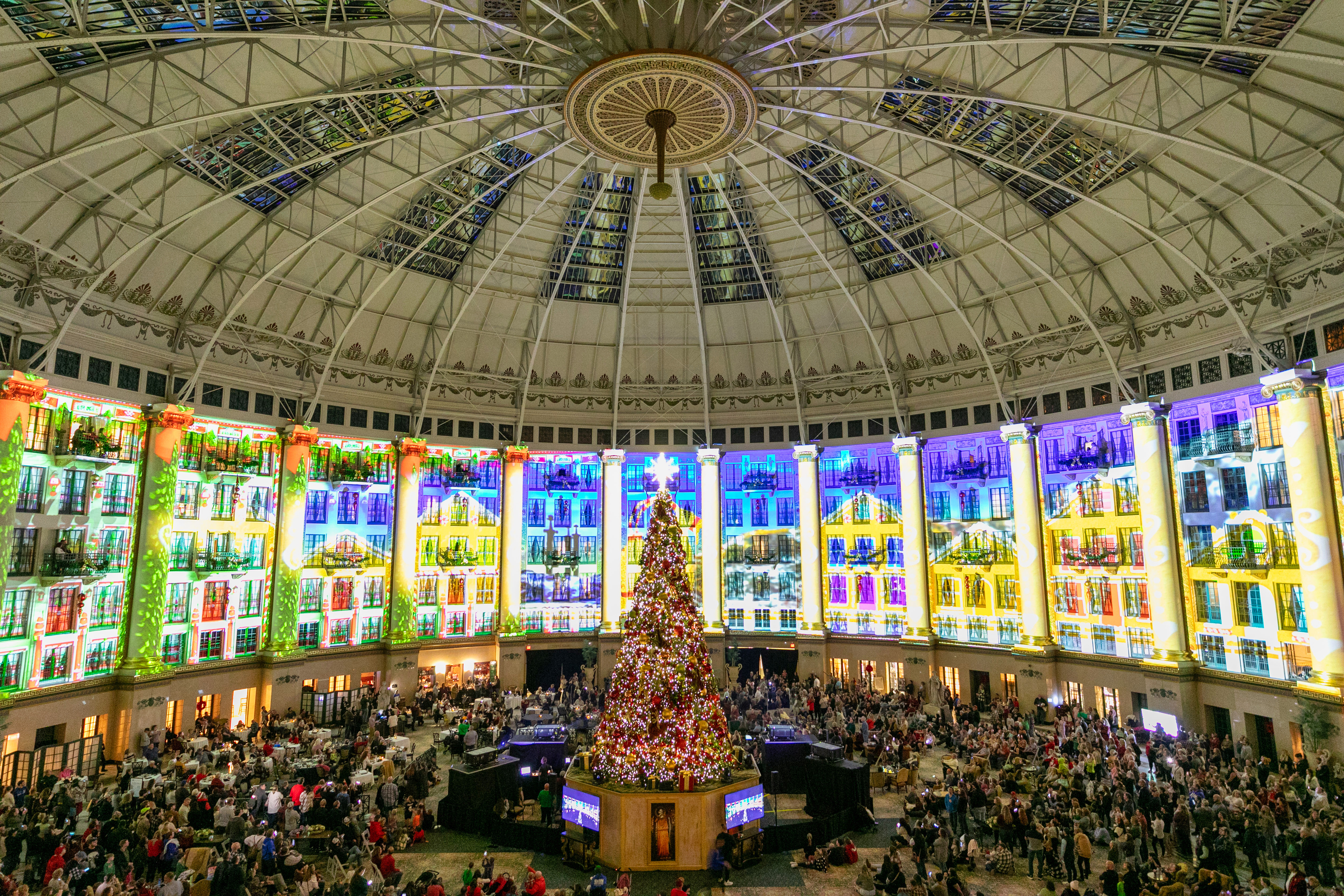 a large room with a large decorated tree and many people