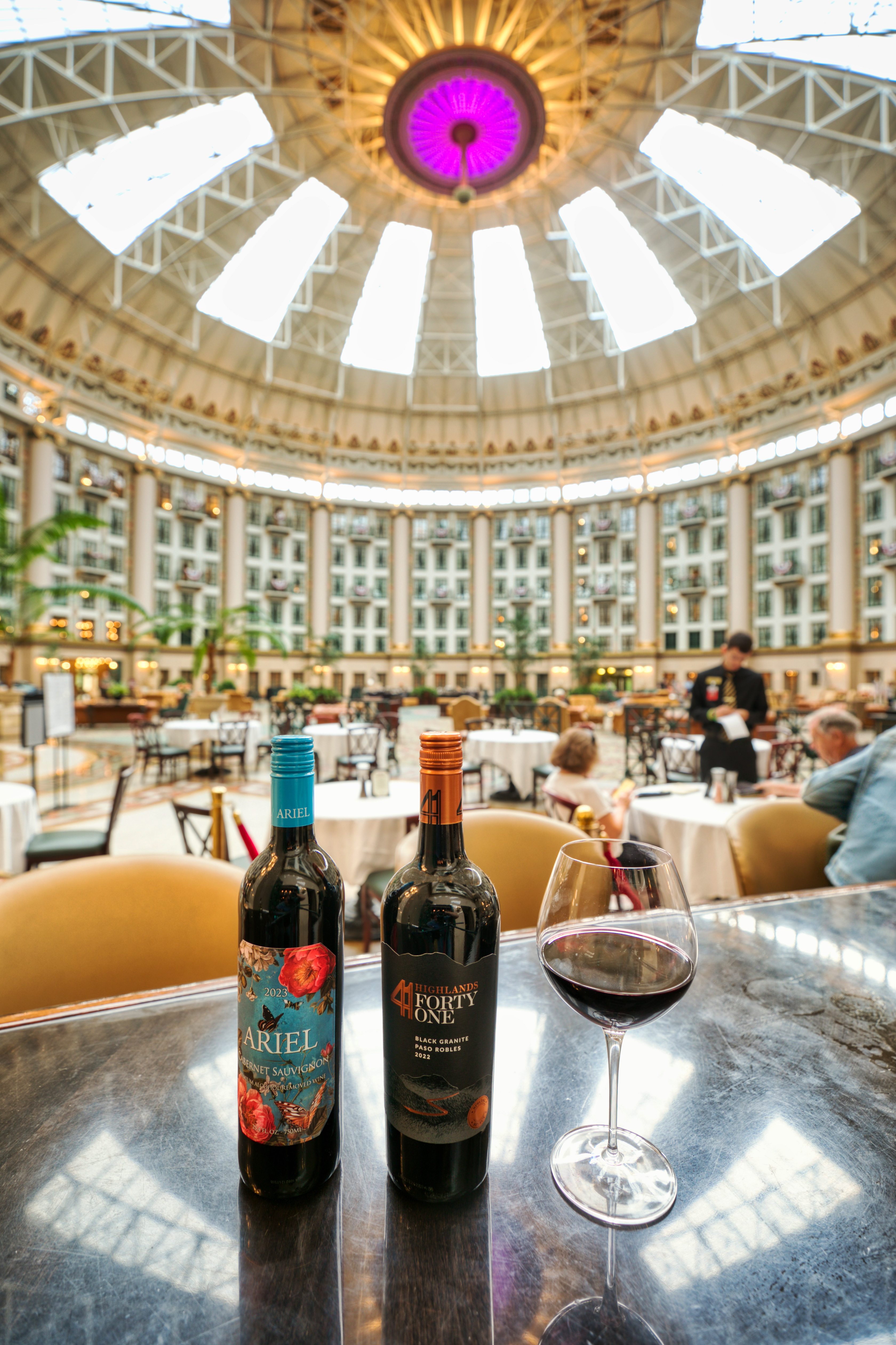 a glass of wine and bottles on a table in a large building