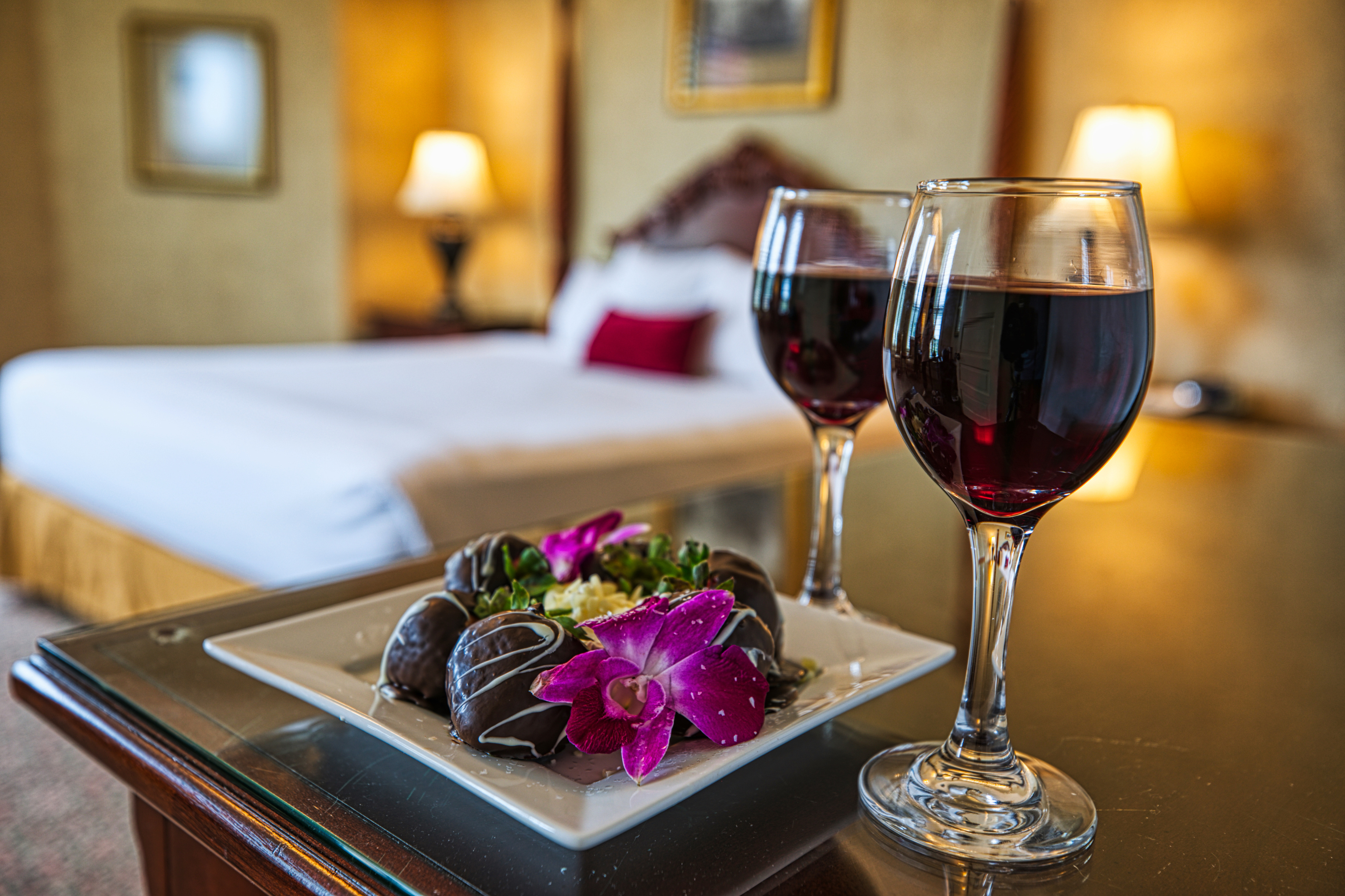 a plate of chocolates and flowers on a table with wine