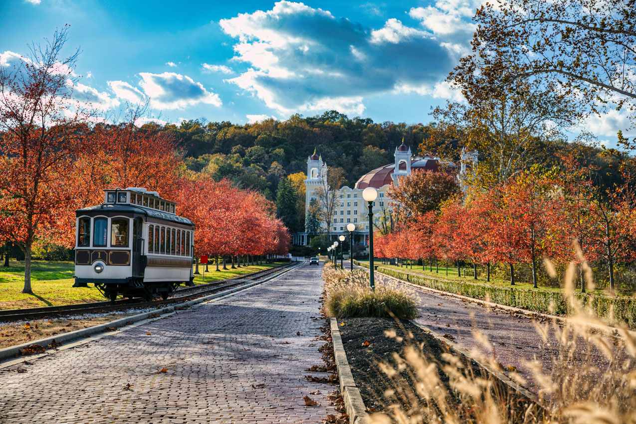 a trolley on a road with trees and buildings in the background