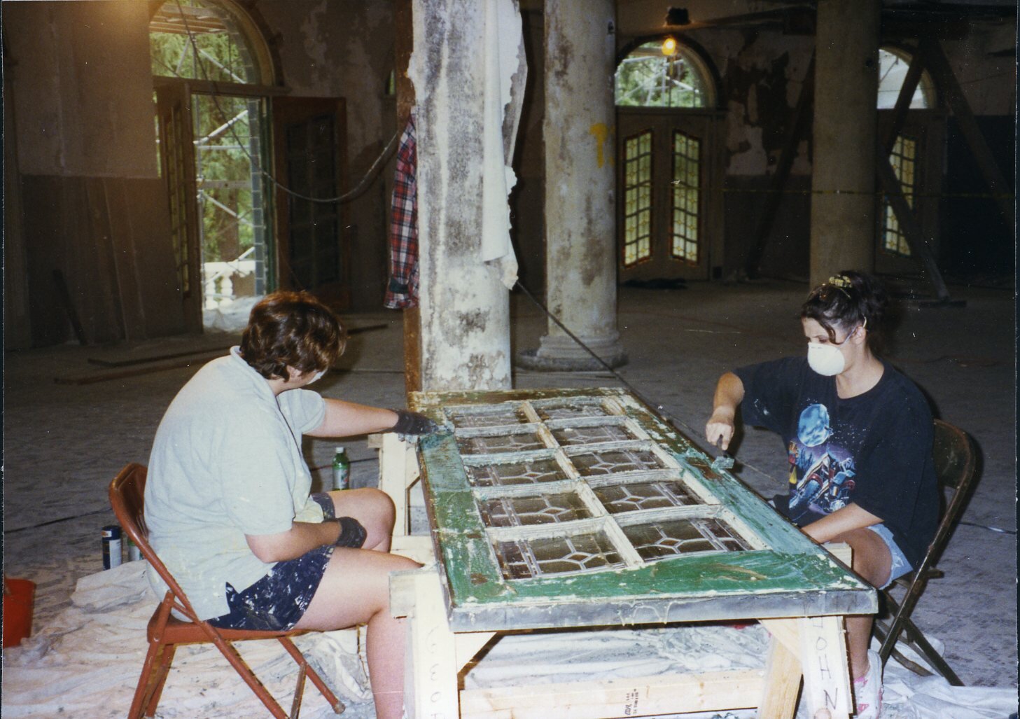 Women scraping paint from an old door