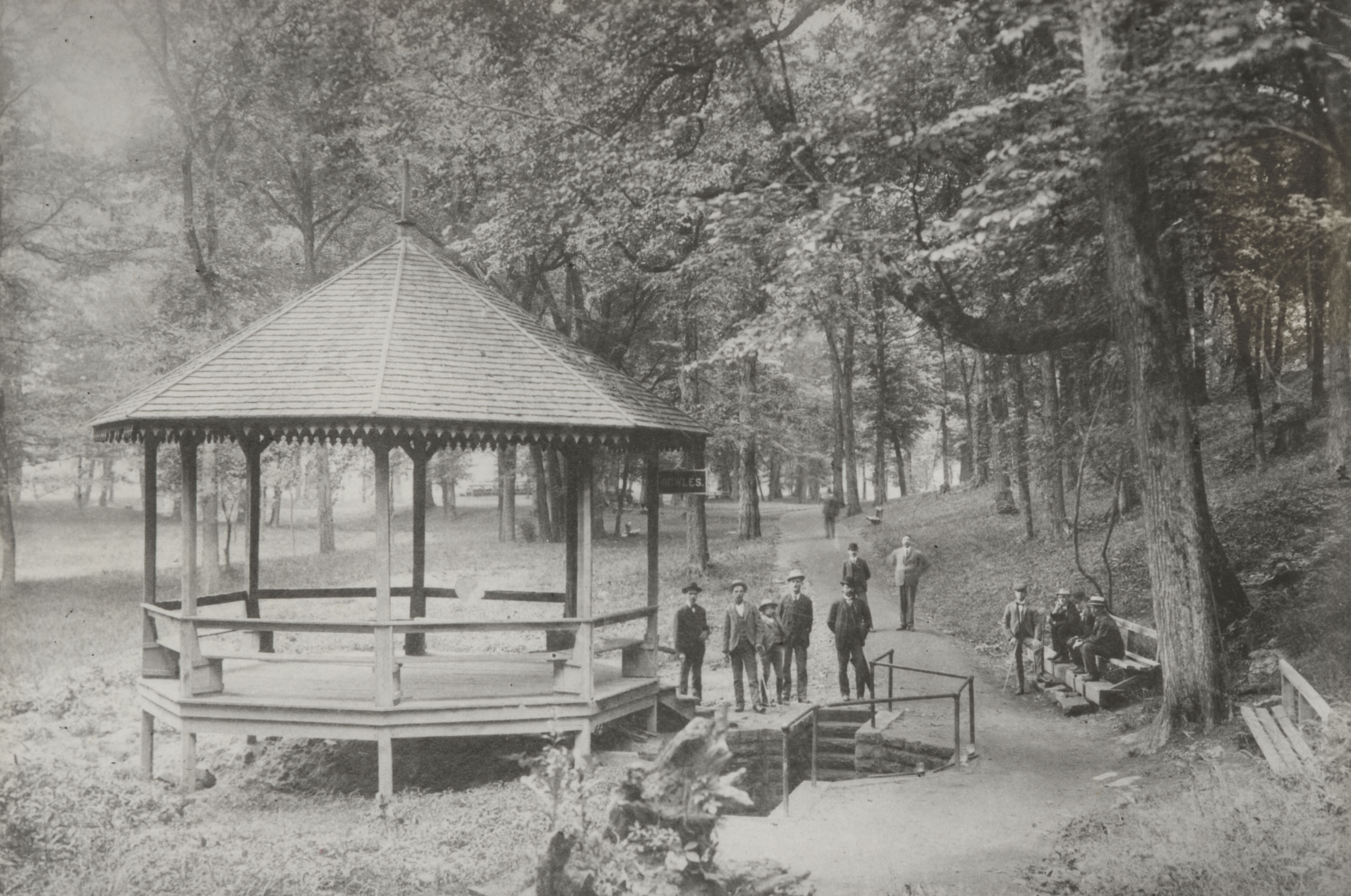 a group of people standing around a gazebo in a park