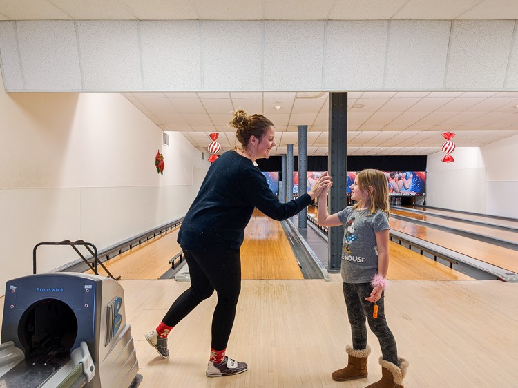 a woman and a girl in a bowling alley
