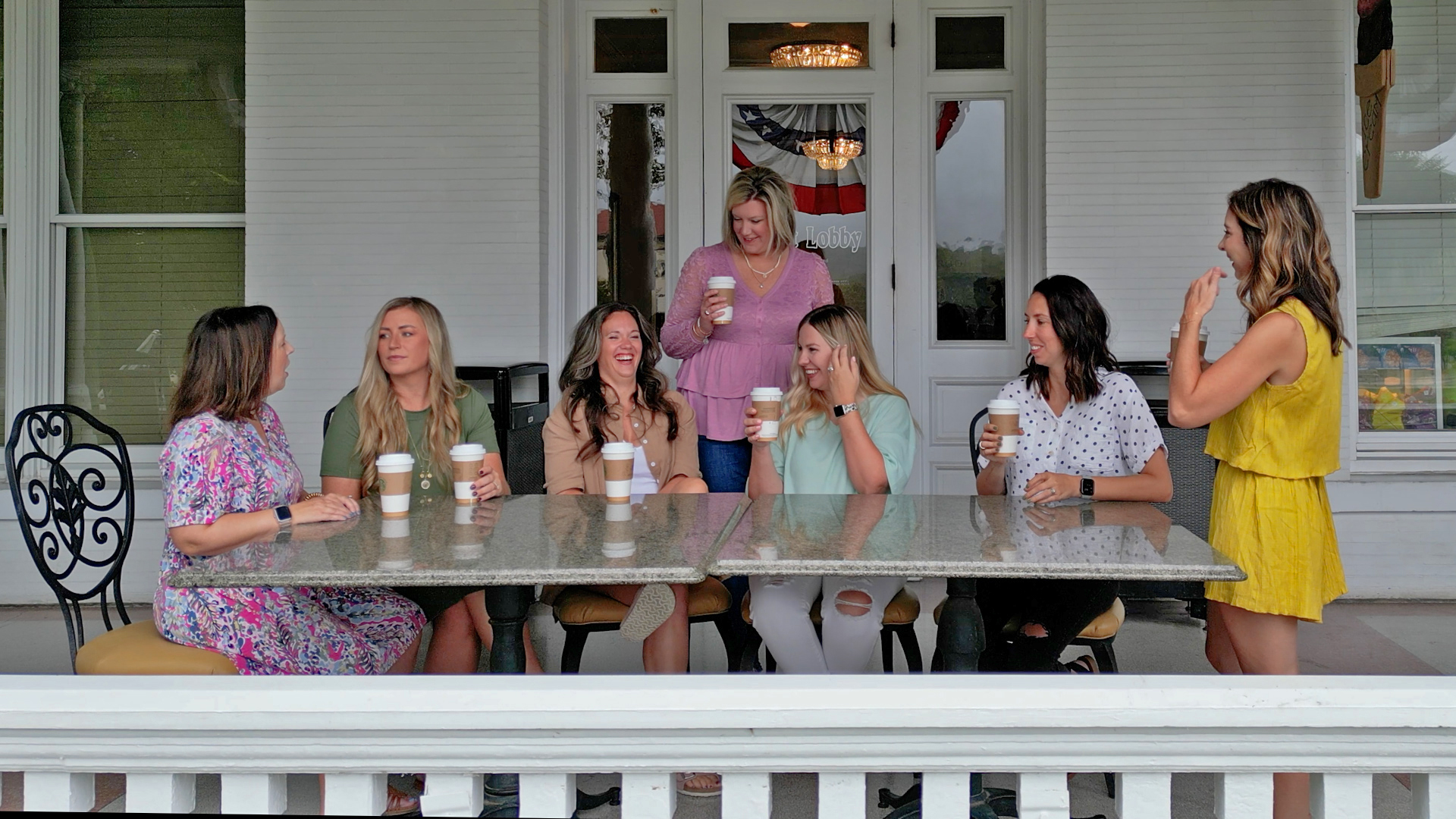 a group of women sitting at a table with cups of coffee