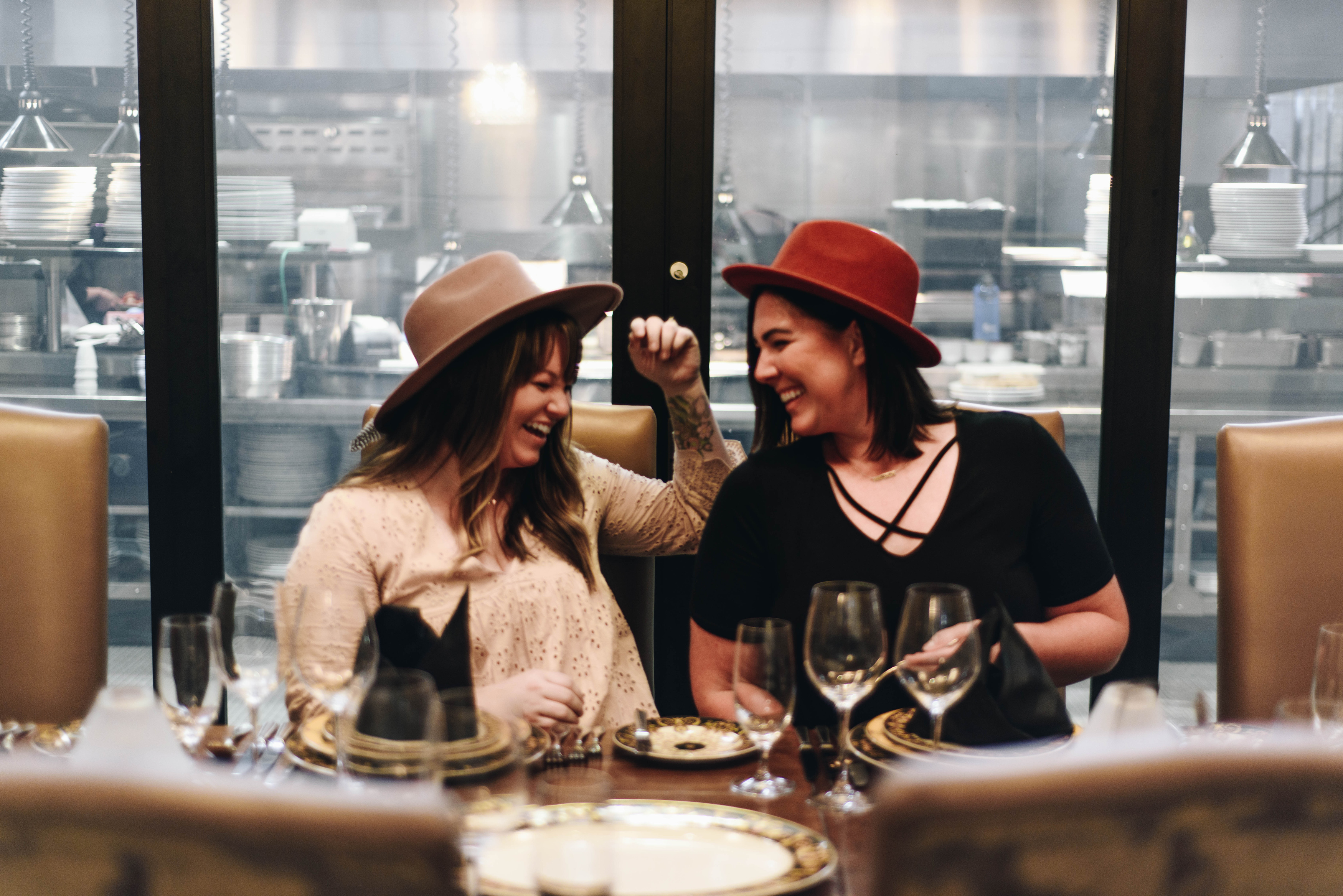 two women sitting at a table with wine glasses and a glass door