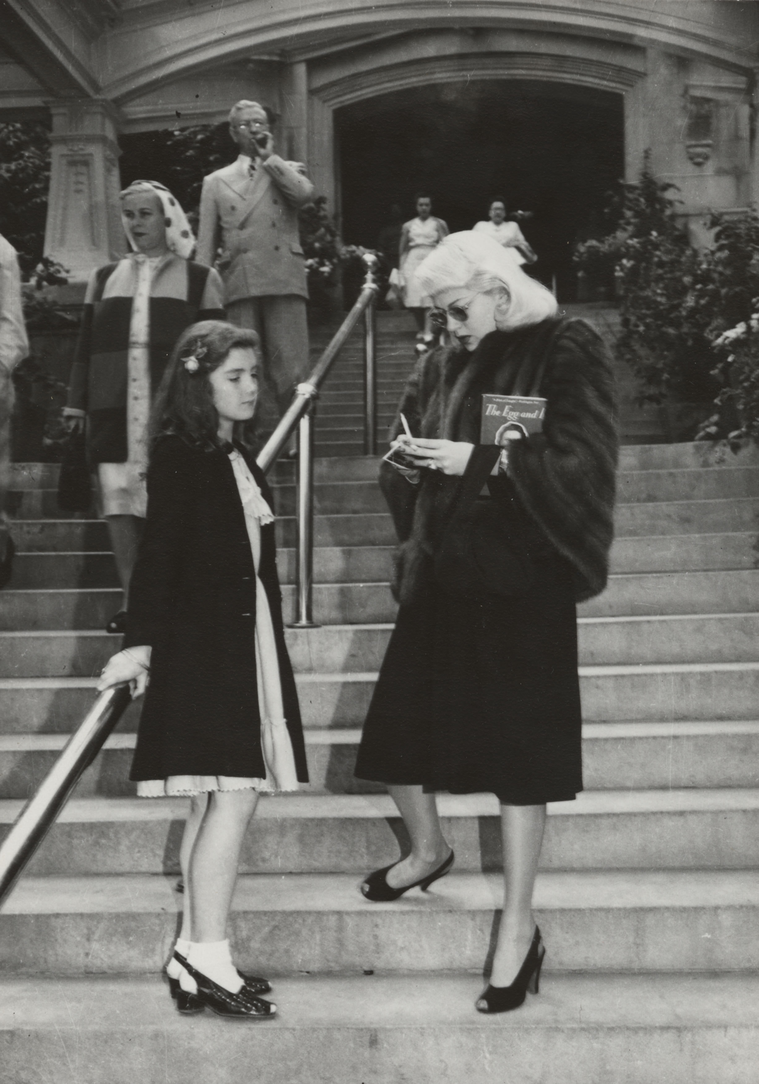 a woman looking at a girl standing on stairs