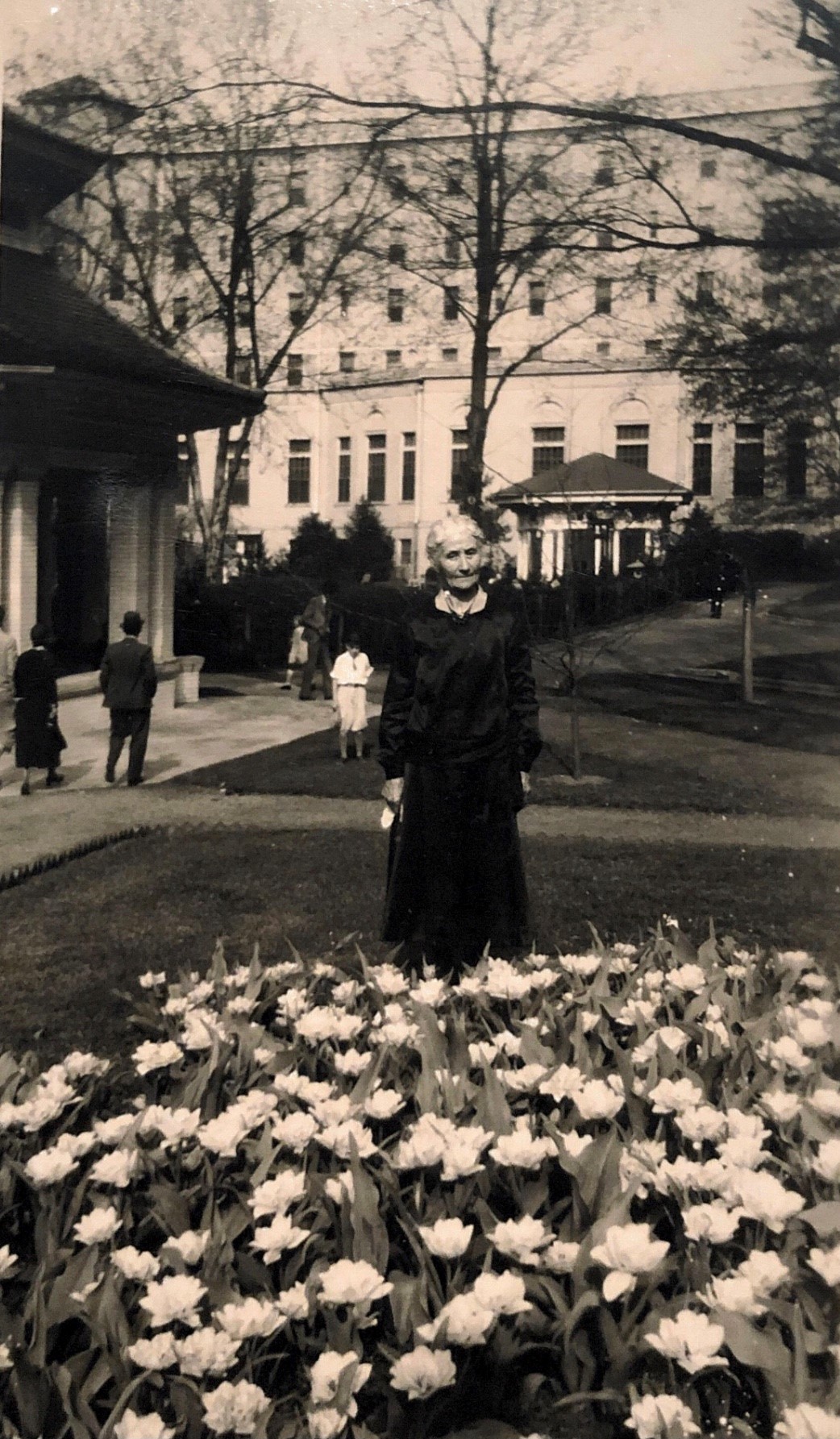 a woman standing in front of a flower bed