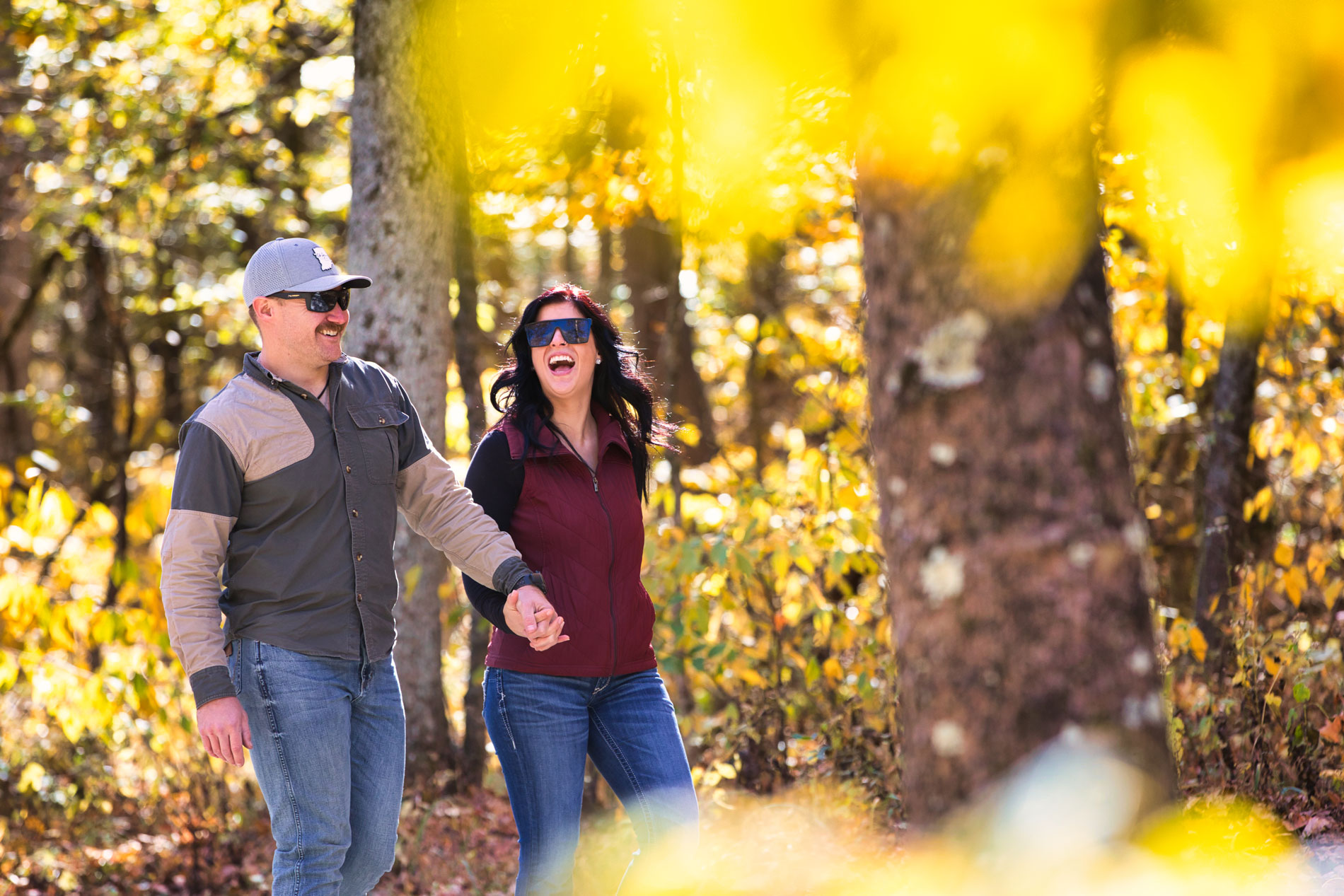 a man and woman holding hands and walking in the woods
