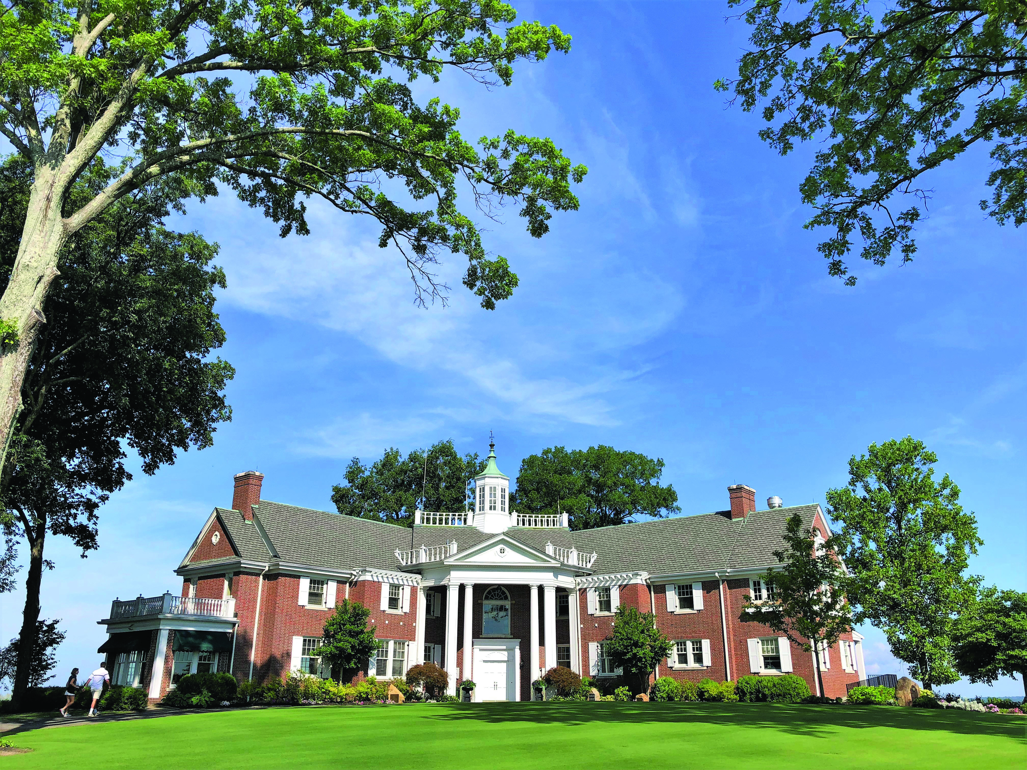 a large brick house with a lawn and trees