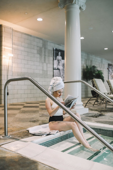 lady sitting on steps of pool with book