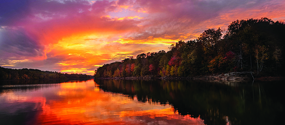 a body of water with trees and a sunset