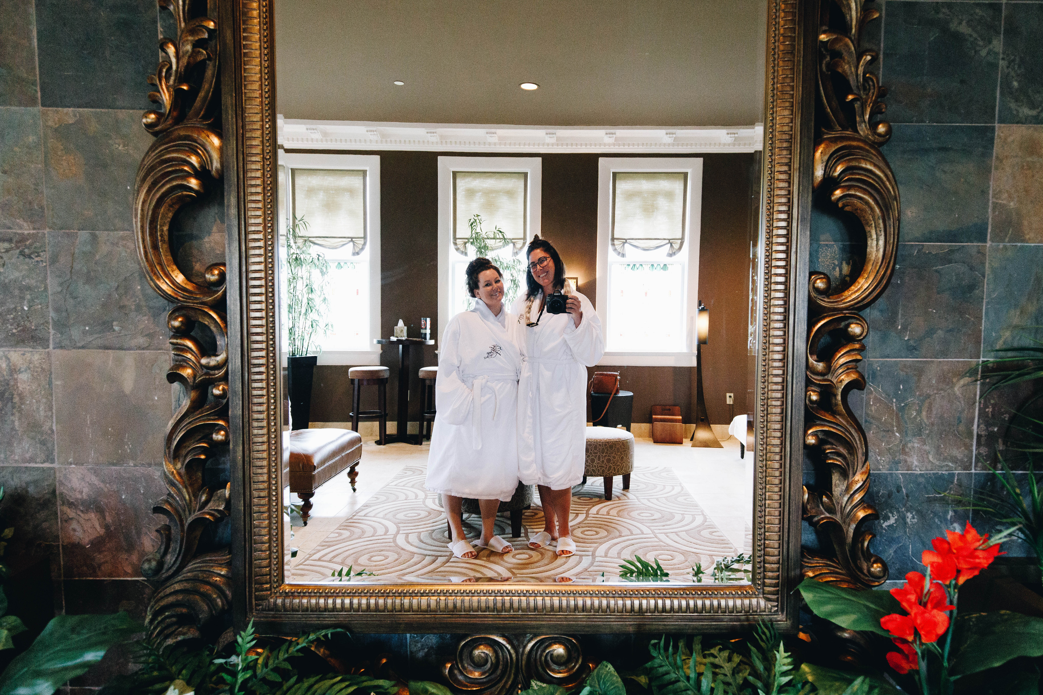 two women in bathrobes posing for a picture in a mirror